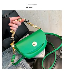 Detail of green saddle bag with silk scarf handle and golden twist-lock closure