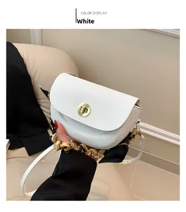 Close-up of white saddle bag with silk scarf wrapped handle and gold twist lock