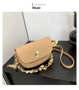 Detail of khaki saddle bag with golden clasp and silk scarf wrapped metal chain