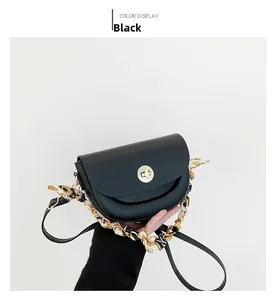 Detail of black leather saddle bag featuring gold rotary lock and silk ribbon chain handle