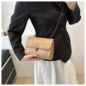 Close-up of beige quilted leather chain bag with a metallic clasp on a model's shoulder