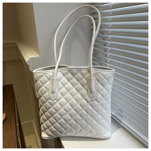 Detail of white quilted leather tote bag showing textured diamond patterns and slim straps