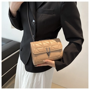 Détail d'un sac à chaîne en cuir matelassé beige avec boucle sur un mannequin en costume