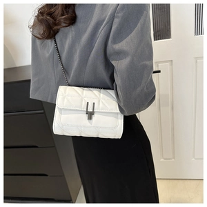 Quilted white crossbody bag with chain strap and metallic lock shown on model's shoulder