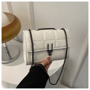Détail d'un sac bandoulière matelassé blanc avec chaîne en métal et fermoir rotatif