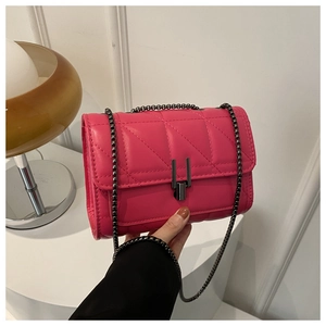 Close-up of hot pink quilted crossbody bag with black metal chain and rectangular lock