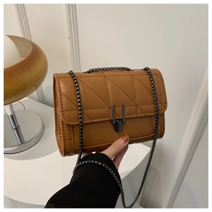 Détail du sac matelassé caramel avec motif en losange et bandoulière en chaîne foncée
