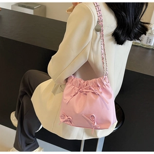 Detail of pink satin bucket bag with handmade bows and metal chain strap