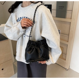 Détail du sac seau noir plissé avec nœuds décoratifs et bandoulière en chaîne argent