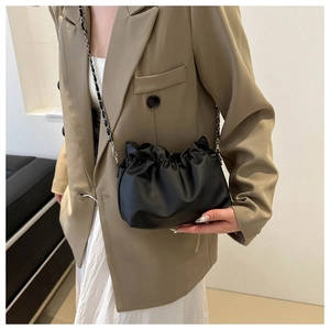 Macro detail of black pleated cloud bucket bag featuring premium texture and silver chain
