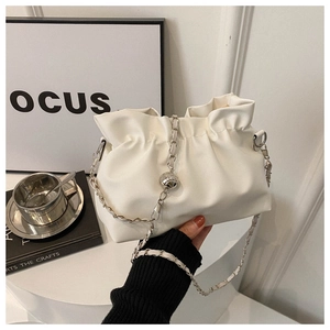 Close-up of white pleated cloud bucket bag with silver chain on a round pedestal