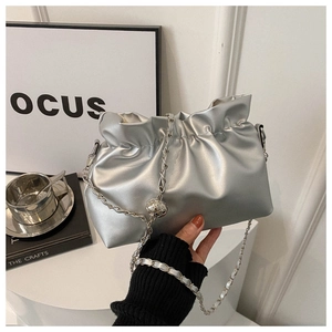 Detail of silver pleated cloud bucket bag with metallic chain and decorative orb