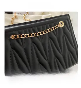 Close-up of black quilted PU leather bag with wave patterns and gold chain details