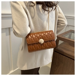 Détail d'un sac matelassé marron avec boucle dorée et texture plissée élégante