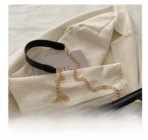 Detail of black quilted shoulder bag with gold chain and leather patchwork strap