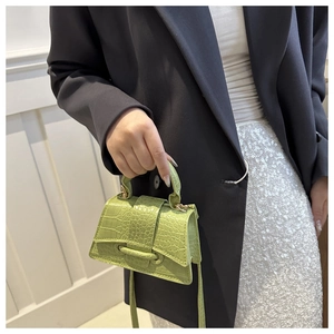Detail of light green crocodile embossed small square bag with top handle for women