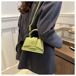 Detail of green crocodile texture mini crossbody bag with tie-style buckle detail