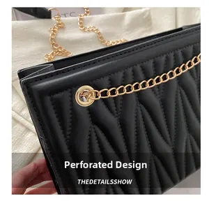 Detailed close-up of golden metal chain and perforated design on black quilted leather bag