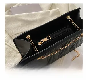 Close-up of the smooth gold metal zipper and internal structure of the black quilted bag