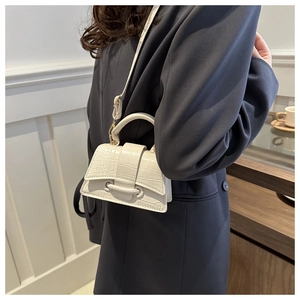 Detail of off-white crocodile embossed leather handbag with top handle and shoulder strap
