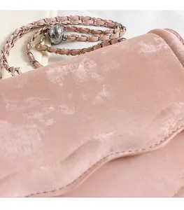 Detailed close-up of pink chain bag with adjustable gold ball charm and velvet fabric