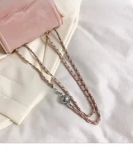 Detailed macro shot of pink leather bag featuring a silver metal ball chain adjuster