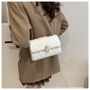 Détail du sac bandoulière blanc matelassé avec chaîne dorée et boucle circulaire