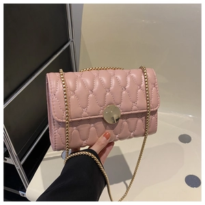 Détail du sac à bandoulière matelassé rose avec texture ondulée et chaîne dorée