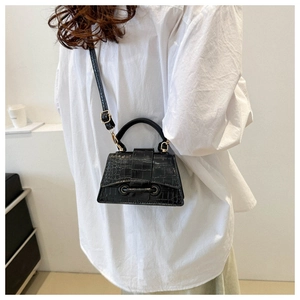 Detail of black faux crocodile leather crossbody bag on white shirt background