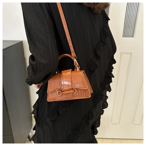 Brown crocodile embossed mini crossbody bag worn by a model on a black dress