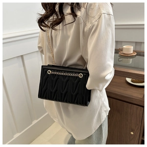 Close-up of black quilted PU tote bag with V-shaped texture and gold chain strap detail