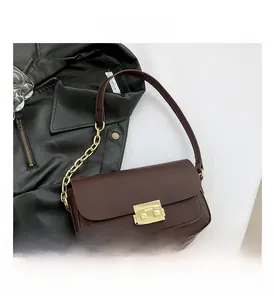 Close-up of a brown leather crossbody bag with golden metal buckle and chain strap