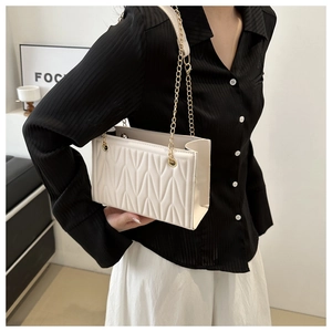 Detail view of cream vertical quilted shoulder bag with elegant gold chain strap
