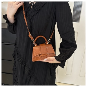 Detail of brown crocodile pattern mini tote bag with gold hardware and top handle