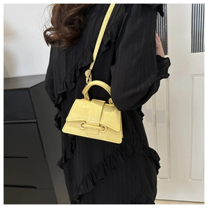 Detail view of a bright yellow crocodile embossed mini crossbody bag with a curved handle