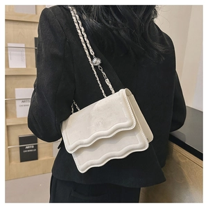Détail d'un sac à bandoulière blanc à rabat ondulé avec chaîne et perle en argent métal