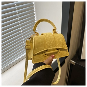 Close-up of yellow crocodile embossed faux leather on a mini designer crossbody bag