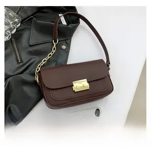 Detail of dark brown leather handbag with vintage gold metal lock and chunky chain strap