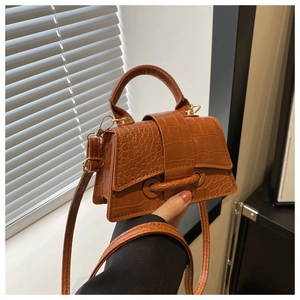 Detail of brown crocodile pattern mini handbag with gold hardware and top handle