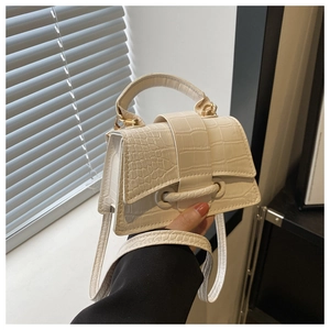 Close-up of cream white crocodile texture handbag with unique circular metal closure