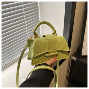 Macro detail of avocado green crocodile embossed faux leather handbag with gold hardware