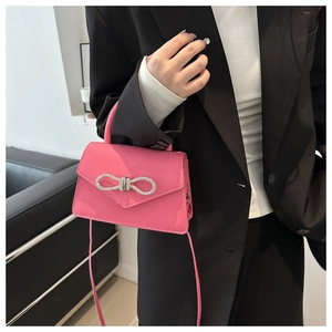 Detail van roze kunstlederen handtas met een sprankelende strass-strik en stiksel