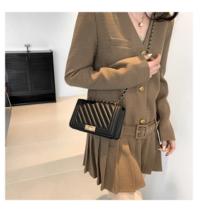 Close-up of black quilted crossbody bag with gold chain strap worn by a model