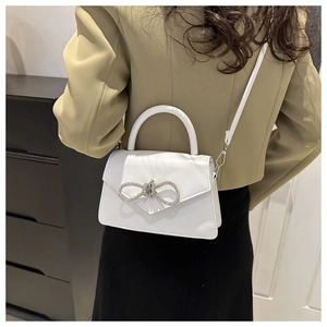 Detail van witte PU-lederen handtas met een grote fonkelende strass-vlindergesp