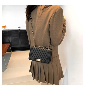 Detail of black quilted leather crossbody bag with gold-tone lock and chain strap
