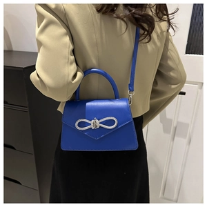 Detail of royal blue handbag with sparkling rhinestone bow buckle and sleek top handle