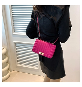 Detail of fuchsia chevron quilted crossbody bag with golden twist lock and chain strap