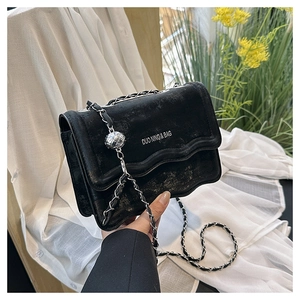 Détail du sac noir à bords ondulés avec chaîne argentée et boule en métal décorative