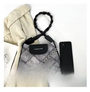 Top view of a grey denim shoulder bag with metal flower chain and smartphone comparison