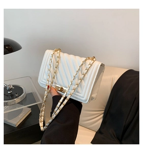 Detailed side view of white quilted crossbody bag with gold chain and metal twist lock